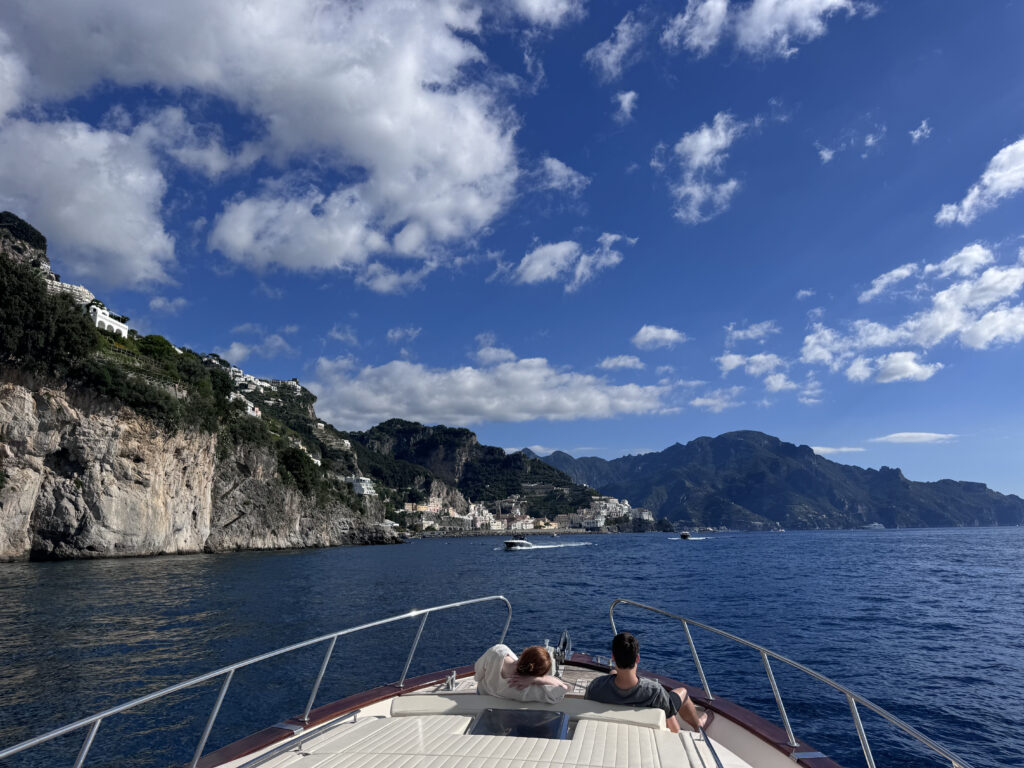 View from the bow of a boat toward Amalfi with cliffs, sea and mountains