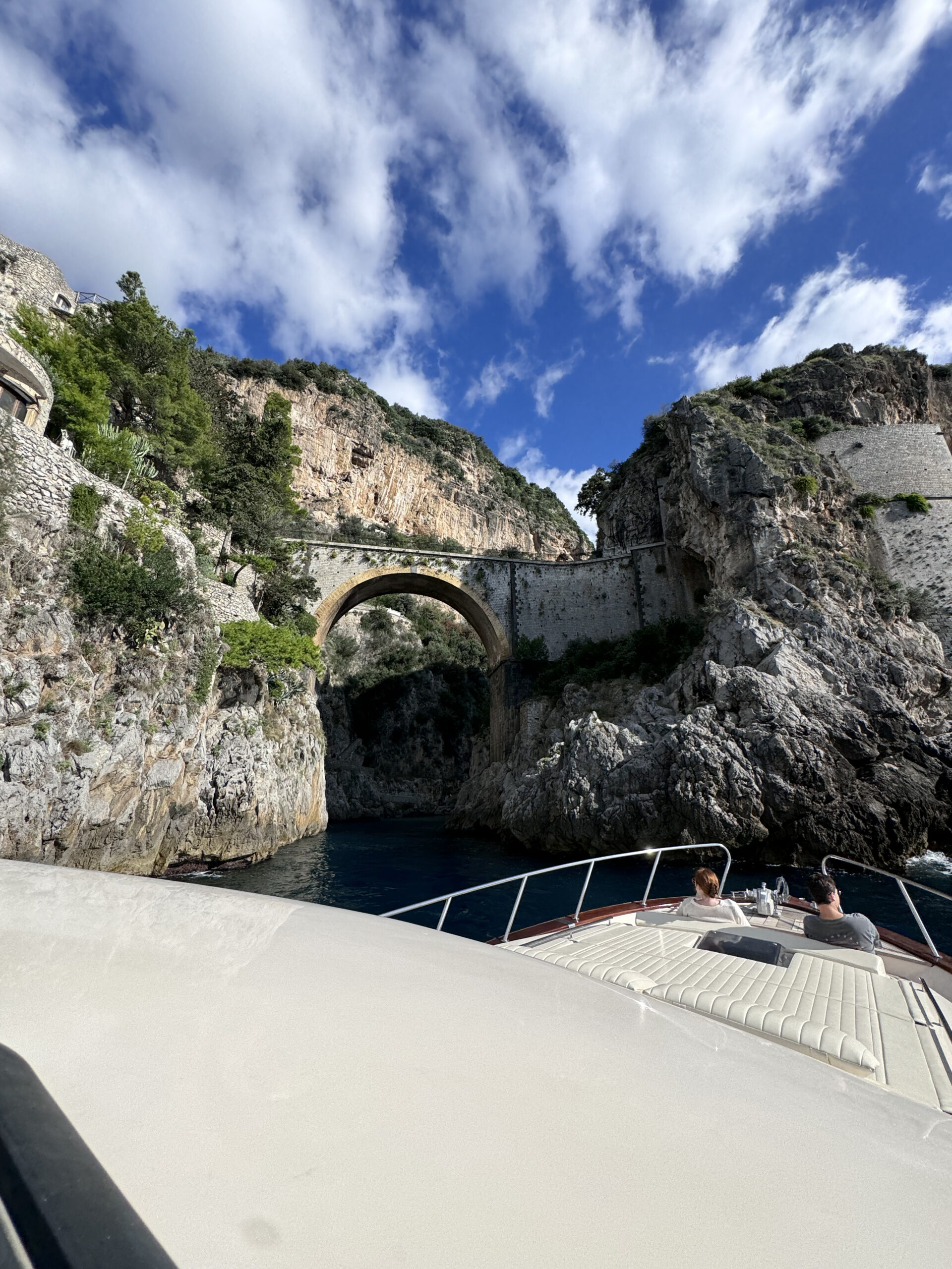 View from a boat of a stone arch bridge and rocky cove in Amalfi-Private boat tour Amalfi Coast - Amare Positano boat experience