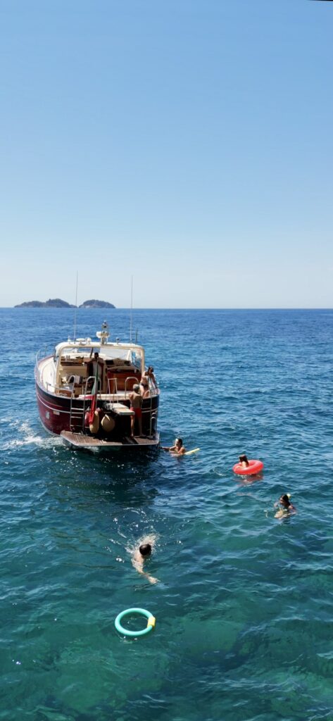 People swimming around a boat during a stop in clear blue water