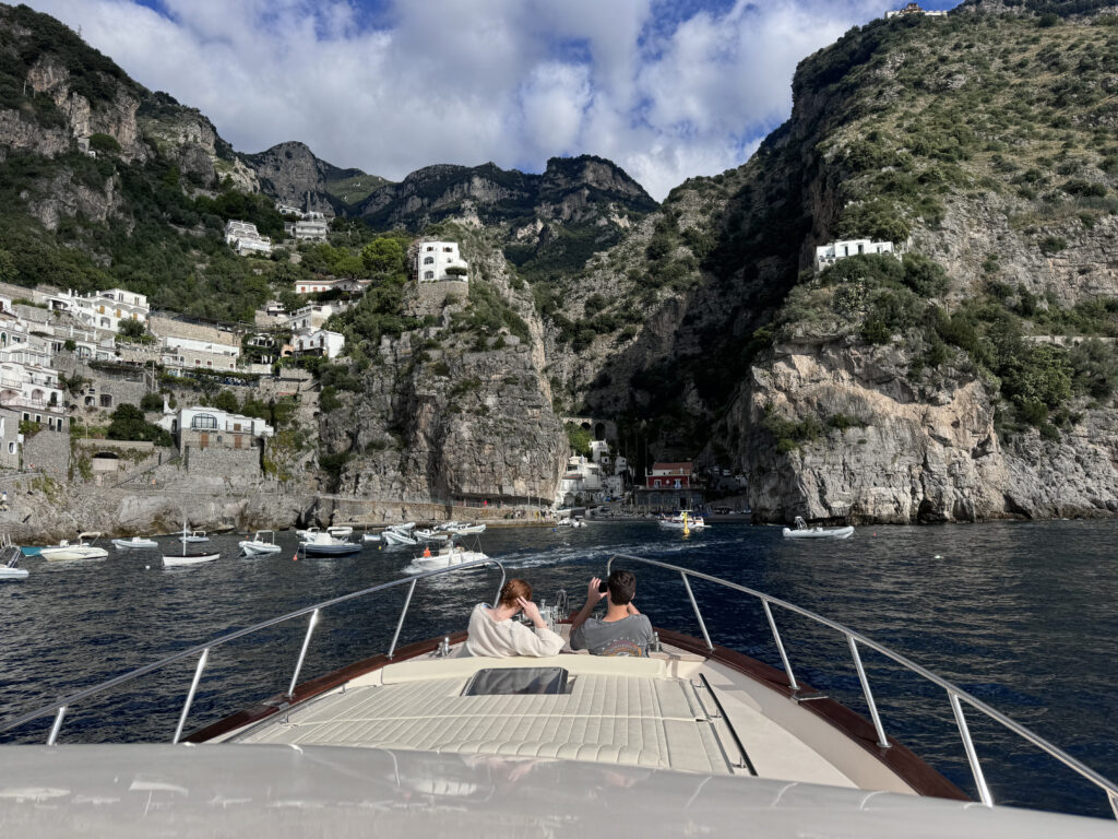 Private Boat tours Positano-View from the bow of a boat toward Positano cliffs with coastal houses and small boats