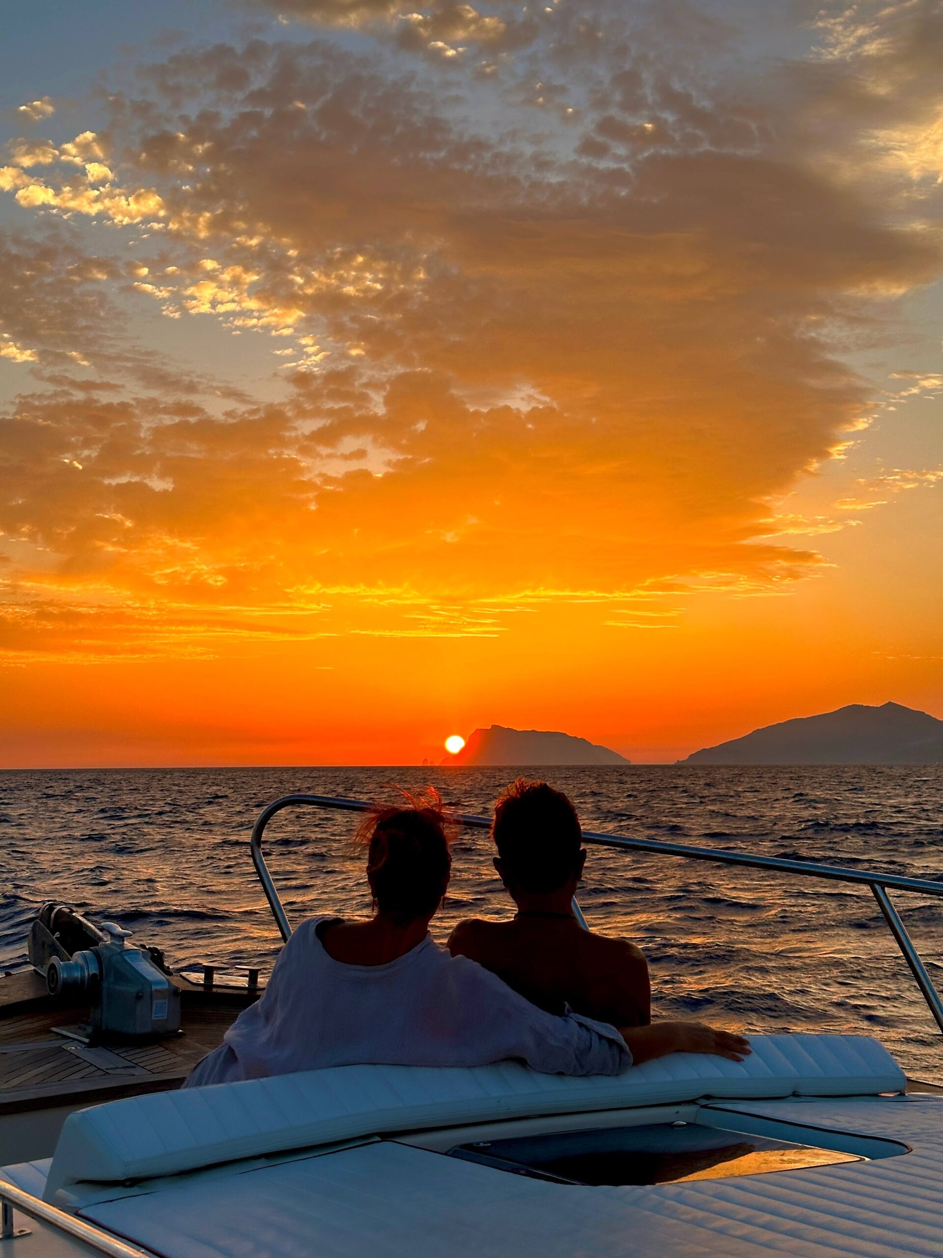 Two people on a boat watching the sunset over the sea