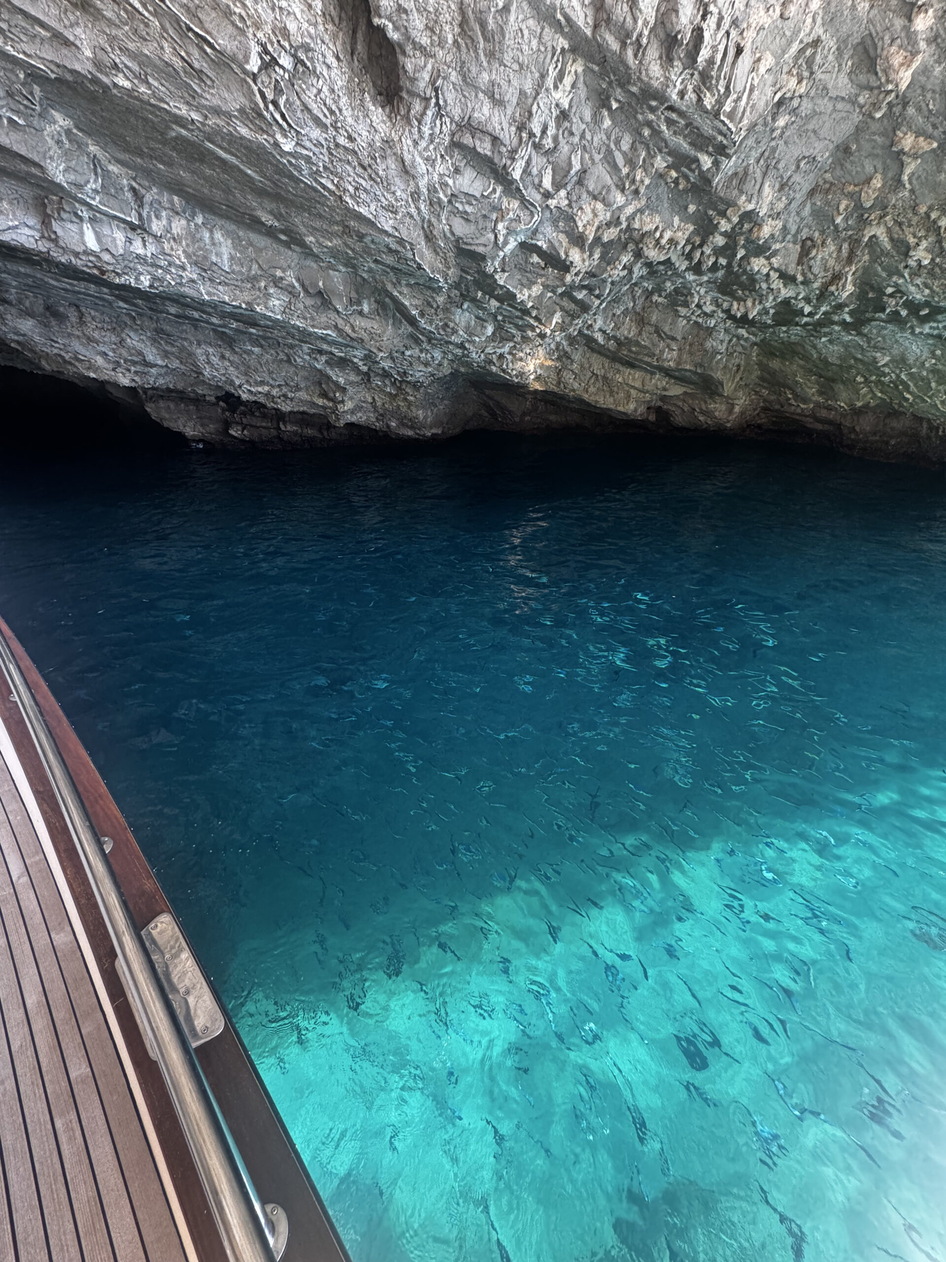Turquoise water near a rocky sea cave seen from a boat